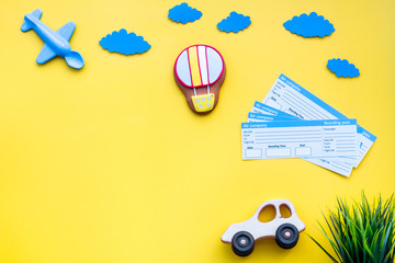 Sample of airplane ticket. Family trip with kid. Airplan, car and air balloon toys. Yellow background flat lay space for text