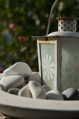 a white lantern in a dish filled with white stones from the beach, Amorgos
