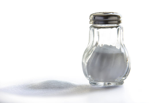 Salero de vidrio con tapa met&aacute;lica sobre fondo blanco