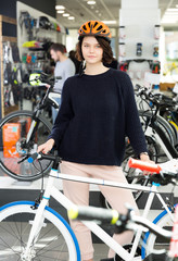 female in helmet standing with sport bicycle