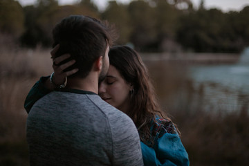 A cute spanish couple having a nice afternoon hugging and kissing each other in a park in front of a lake in Seville, Spain.