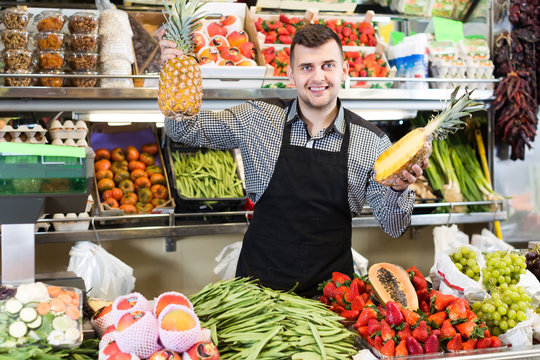 active male seller showing assortment of grocery shop