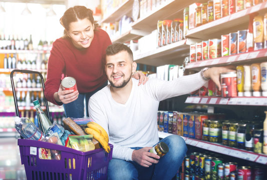 satisfied couple choosing purchasing canned food for week at supermarket