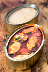 metal cans with tuna and mussels, on rustic wooden board