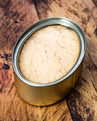tin of metal with pickled tuna, on wooden rustic board