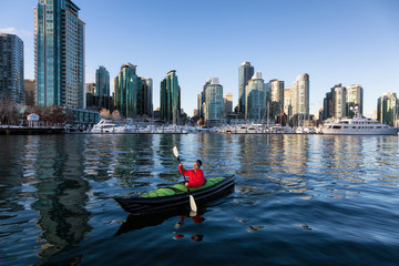 Man on an inflatable kayak is kayaking in Coal Harbour during a sunny morning. Taken in Downtown Vancouver, British Columbia, Canada. © edb3_16