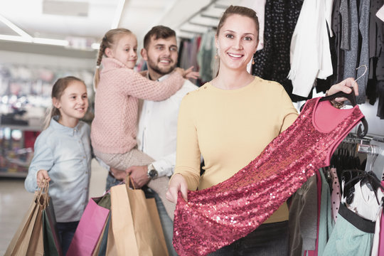 Young mother choosing new dress in shop