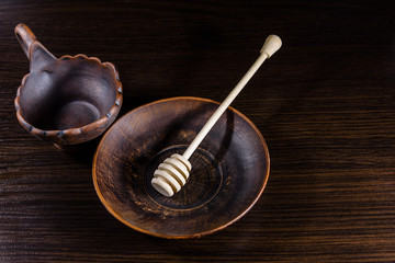 Honey spoon in the ceramic dish on dark wooden table