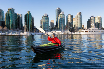 Man on an inflatable kayak is kayaking in Coal Harbour during a sunny morning. Taken in Downtown...