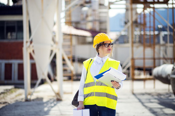 A Woman Quality Control Inspector Wearing a Safety Jacket and Hard Hat