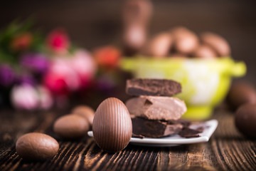A chocolate Easter eggs with raw chocolate on a wooden backdrop