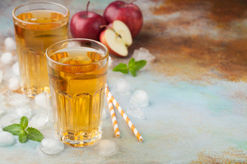 Two glasses of red Apple juice with mint and ice on an old rusty table. Soft drink on a blue background. With copy space