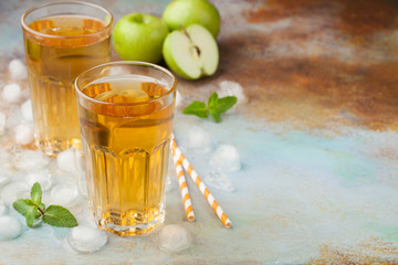 Two glasses of green Apple juice with mint and ice on an old rusty table. Soft drink on a blue background. With copy space
