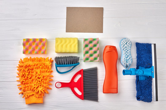 Multiple house cleaning products. Brushes and sponges for house cleaning on white wooden background. Spring cleaning guide.