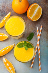 Two glasses with freshly squeezed orange juice and mint on an old rusty blue background. Top view