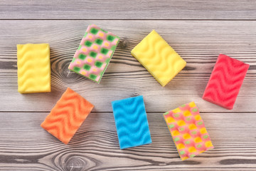 Multicolored kitchen sponges, wooden background. Set of colorful sponges for washing dishes on wood. House cleaning supplies.