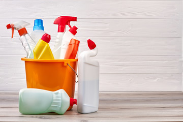 Bucket with cleaning supplies, copy space. Cleaning supplies kit on wooden background. Cleaning...