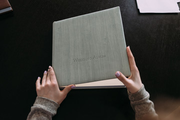 Naklejka premium The hands open the cover of the photobook