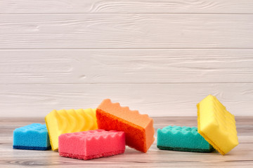 Colorful cleaning sponges on wooden background. Multicolored kitchen sponges on wood, copy space.