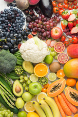Healthy eating background, assortment of different fruits and vegetables in rainbow colours on the off white table arranged in a rectangle, top view, selective focus