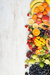 Assortment of fresh fruits and vegetables in rainbow colours on the off white table verical, top view, selective focus