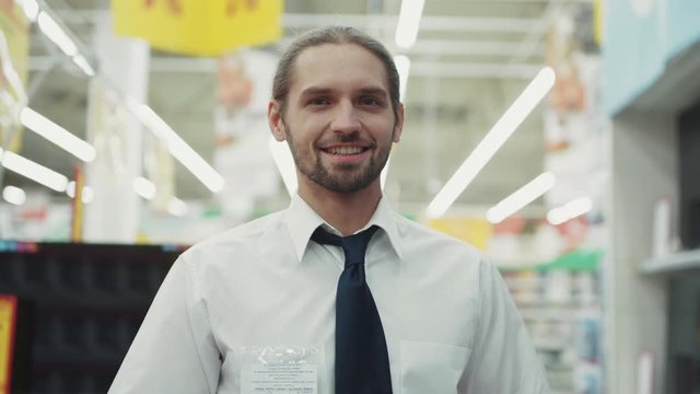 Attractive man the seller work look at camera in tech department in supermarket feel happy business hand shopping electronics technology internet mall slow motion close up portrait handsome