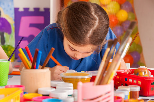Small students painting in art school class. Child drawing by paints on table. Boy and girls in kindergarten. Drawing education develops creative abilities of children. Hobby for teenagers.