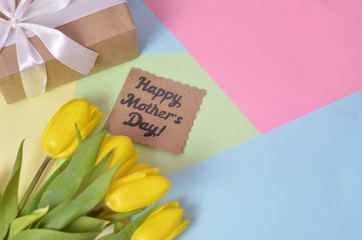 happy mother's day text sign on pink tulips on white rustic wooden background. greeting card concept. sensual tender women image. spring flowers flat lay