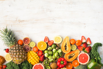 Fruits and vegetables rich in vitamin C, oranges mango grapefruit kiwi kale pepper pineapple lemon sprouts papaya broccoli, on wooden white table, top view, copy space, selective focus - obrazy, fototapety, plakaty