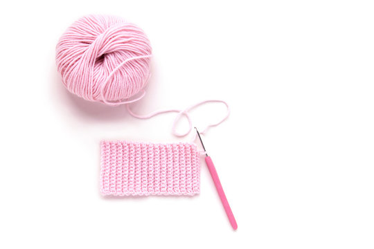 Ball of pink knitting yarn and knitting crochet on white background. Flat lay, top view. Handmade.