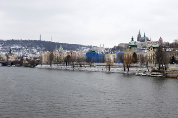 Obraz premium Snowy Prague Lesser Town with gothic Castle above River Vltava, Czech republic