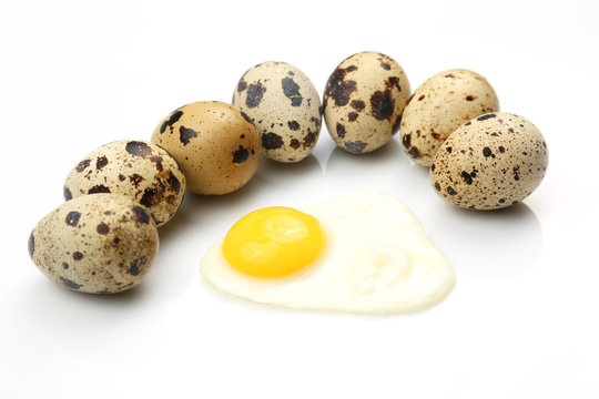 quail eggs on white background around fried eggs.