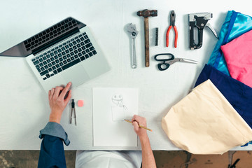 Man from above working in his craft workshop. Designer in the workshop drawing a carnival costume