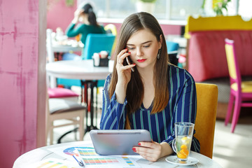 A young person works on a tablet and speaks on a mobile phone. The concept of work, business, education, freelance, lifestyle.