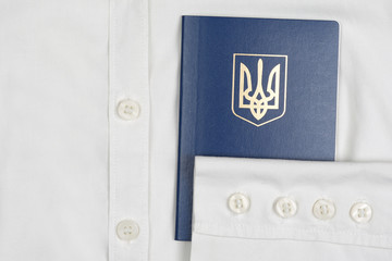blue passport of Ukraine lies on a white shirt.