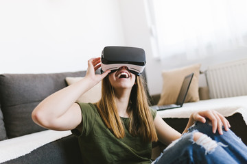 Beautiful young woman enjoying virtual reality at her home.