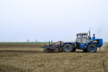 Obraz premium Lush and loosen the soil on the field before sowing. The tractor plows a field with a plow