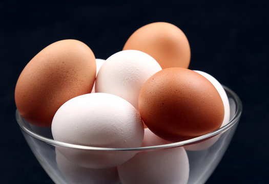 chicken eggs lie in plate on dark background.