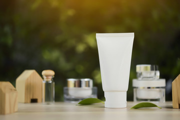 White cosmetic products and green leaves on white background. Natural beauty products for branding mock-up concept.