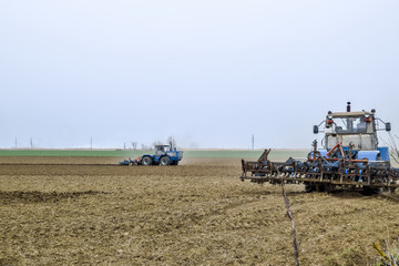 Fototapeta na wymiar Lush and loosen the soil on the field before sowing. The tractor plows a field with a plow