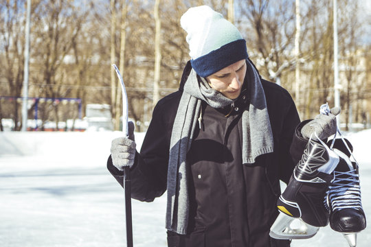 young man carry hockey equipment on a skate rink on a winter day