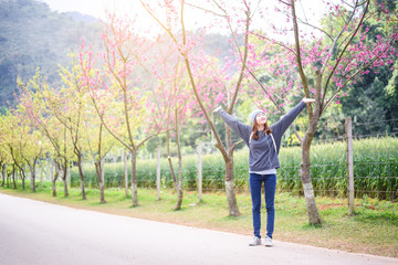 Fototapeta na wymiar Happy woman traveler relax feel free with cherry blossoms or sakura flower tree on vacation