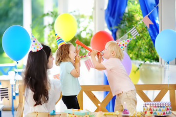 Little child and their mother celebrate birthday party with colorful decoration and cakes with...