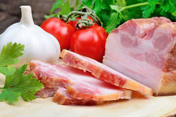 Sliced of bacon with cherry tomatoes, garlic and parsley on table
