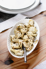 Herbed and pickled artichoke hearts on serving platter on wooden table