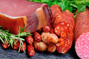 Prosciutto, sausages and salami with herbs on table