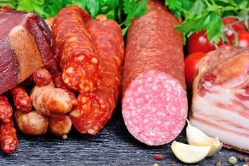 Salami, bacon and sausages with spices on table