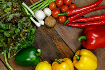 Red Chili Peppers, Yellow Chili Peppers, Green Chili Peppers, Tomato, Lemon, Eggplant, Green oak, and the vegetables put a circle on the old wooden floor.