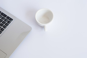 Close up laptop and empty cup of coffee  on the table.