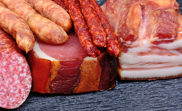 Bacon with sausages, prosciutto and salami on table